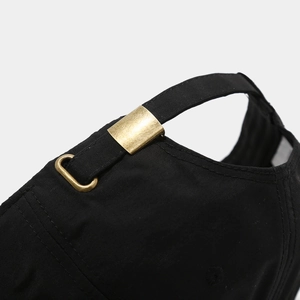 Détail de la boucle métallique réglable et des coutures denses sur la casquette noire