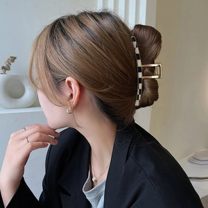 Elegant checkered metal hair claw clip with golden finish on female model hair