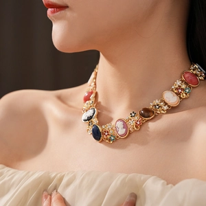 Detail of vintage necklace with cameo pendants and colorful gemstones on a model