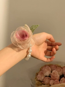 Macro detail of a romantic organza flower wrist corsage with elegant pearl chain accents