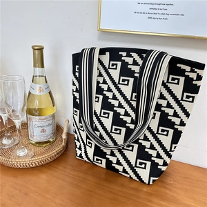 Detail shot of black and white geometric knit tote bag with a woven texture and wide strap