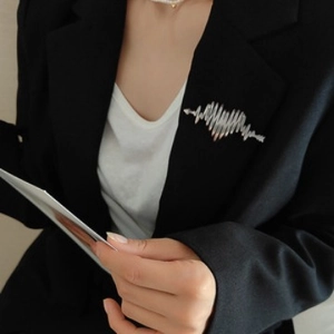 Silver heartbeat EKG heart brooch pinned on black suit lapel for minimalist styling