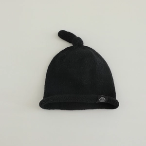 Détail du bonnet tricoté noir pour bébé avec nœud supérieur et bordure roulée