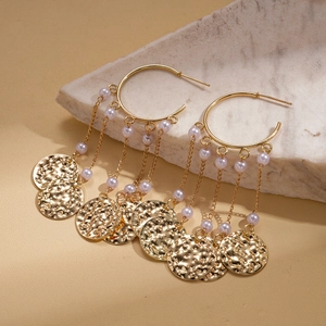 Detail of gold tassel earrings with hammered discs and pearls on natural stone background