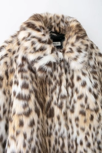 Detail close-up of premium leopard print faux fur coat collar and brand size label