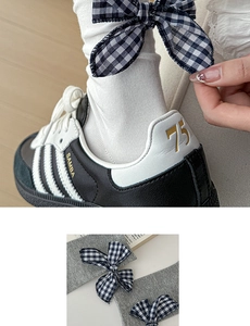 Detail of grey and white cotton socks with blue plaid bow tie and ribbed texture