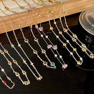 Detailed shot of gold-plated necklaces with colorful cubic zirconia and pearl charms