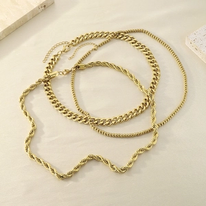 Detailed stack of three golden stainless steel necklaces including cuban and rope chains