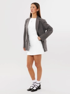 Close-up of a dark grey blazer styled with a white mini dress for a chic urban look