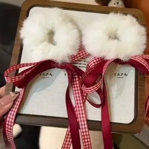 Detail of plush white faux fur hair clips with long red and checkered ribbon bows