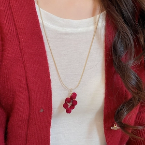 Detail of red grape fringe necklace worn with a stylish winter knit cardigan
