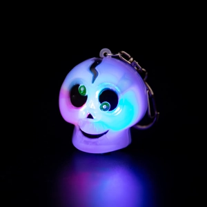 Close-up of glowing LED skull keychain with colorful lighting and metal ring for bags
