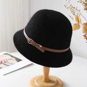 Detail of wool cloche hat with a brown leather buckle strap on a wooden stand