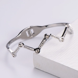 Macro shot of silver-tone wavy bangle with sparkling rhinestones on wood display