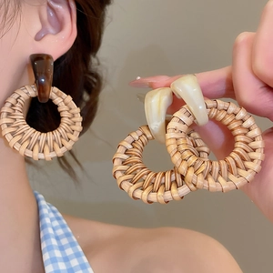 Detail of bohemian rattan hoop earrings with resin accents on a model and handheld