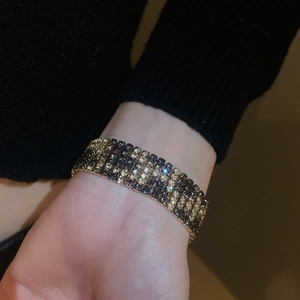 Close-up of multi-row rhinestone bracelet in black-gold finish on female wrist