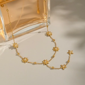 Golden North Star jewelry set with necklace and floral accents on a glass bottle