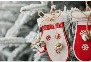 Close-up of a red wooden glove ornament with snowflake patterns and small bells