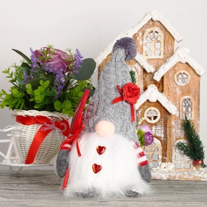 Détail d'un gnome de Noël avec bonnet gris en tricot, rose rouge et barbe blanche