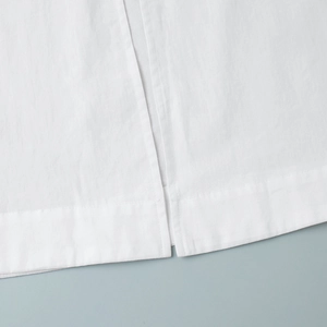 Close-up of split hem design on a white cotton dress featuring reinforced stitching