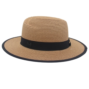 Close-up of woven panama straw hat with black grosgrain ribbon and metal M letter logo