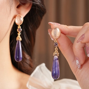 Gros plan des boucles d'oreilles pendantes violettes style vintage avec bordure dorée