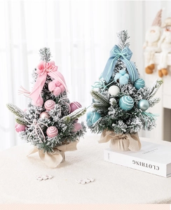 Close-up of pink and blue flocked mini Christmas trees with burlap base and bows