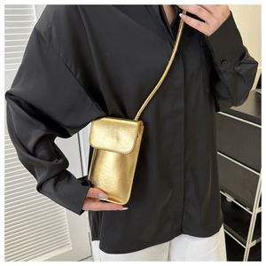 Detail of a minimalist gold PU leather crossbody phone bag on model wearing black shirt