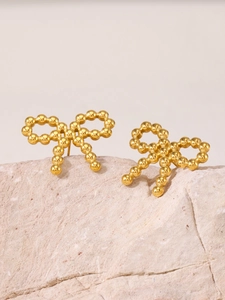 Détails macro des boucles d'oreilles nœud dorées perlées sur une pierre naturelle