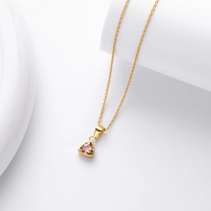 Macro detail of a minimalist gold necklace with a champagne triangle cut gemstone pendant