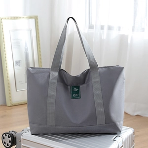 Large gray canvas travel duffel bag on a silver suitcase with soft natural lighting