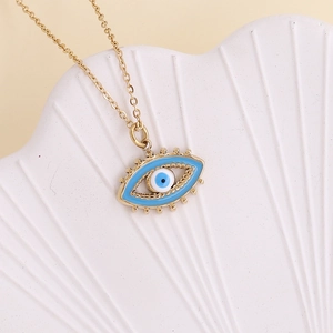 Detail of a golden Evil Eye pendant with blue enamel on a white shell prop