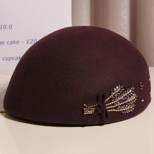 Detailed embroidery of rhinestones and beads on a deep burgundy wool felt beret