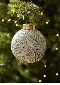 Detailed view of an 8cm white Christmas ball with green leaf texture on a pine branch
