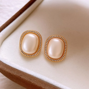 Close-up of vintage oval pearl earrings with gold frame and crystals in beige velvet box