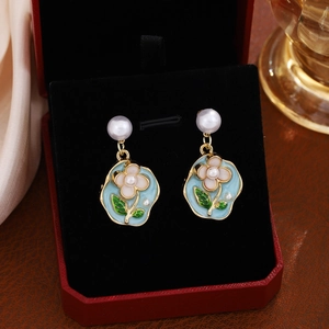 Detail of floral enamel earrings with blue petals, pink flowers and a white pearl accent