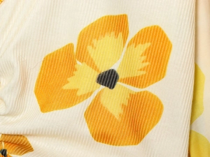 Macro shot of fine ribbed knit fabric with cream base and orange floral patterns