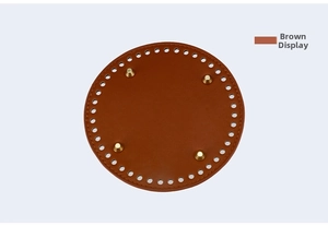 Close-up of a brown circular leather bag base with golden feet and pre-punched holes