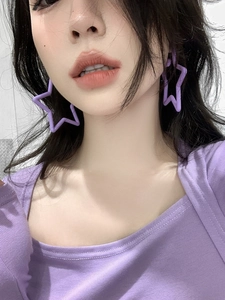 Close-up of purple star-shaped acrylic earrings worn by a model with soft lighting