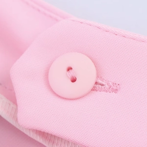 Gros plan du tissu du blazer rose montrant la texture sergée et le bouton rond assorti