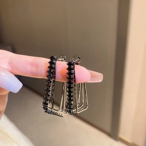 Macro shot of geometric rectangular dark metal earrings with black crystals and studs