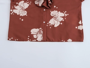 Gros plan détaillé du chemisier marron à fleurs avec boutons blancs et volanté
