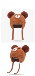 Detail view of winter baby knit hat with bear face embroidery and dual pom-poms