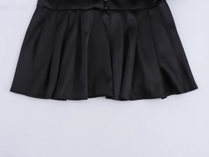 Detail of black satin dress showing elegant pleats and smooth texture on white background