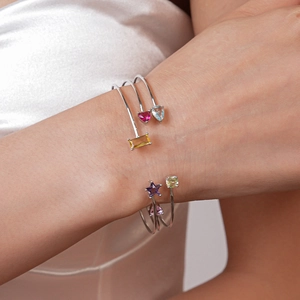 Détail de trois bracelets argentés ornés de zircons colorés en formes de cœur et d'étoile