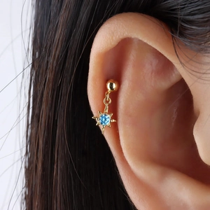 Close-up of golden S925 sterling silver ear stud with blue zircon star pendant on ear