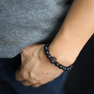 Detail of matte black beads and lion head charm on a stylish men's wrist bracelet