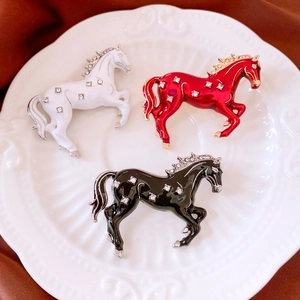 Macro detail of enamel horse brooches with crystal inlay on an elegant ceramic plate