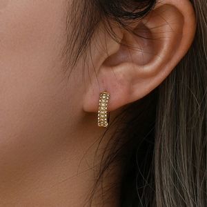 Orecchini a cerchio dorati 18K con zirconi bianchi indossati, stile minimal lussuoso
