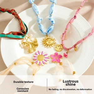 Flat lay of silk ribbon necklaces with vintage gold charms and enamel floral pendants